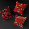 Three distinct red MUNACHU African pillow covers with unique designs, filled with pillows and floating against a black background