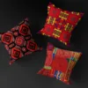 Three distinct red MUNACHU African pillow covers with unique designs, filled with pillows and floating against a black background